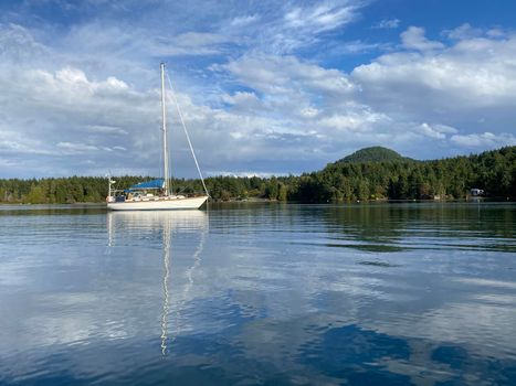 Sailboat in a beautiful and peaceful cove with blue skies. Located in Winter Cove, Gulf Islands National Marine Park