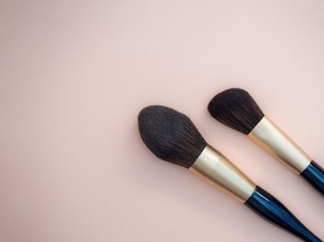 Assortment of female make-up of various face brushes. A set of professional dark blue and golden makeup brushes on a pink background. photo