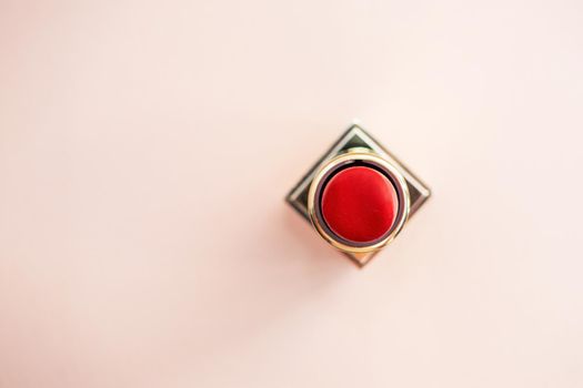 red lipstick in a gold case on a pink background. photo