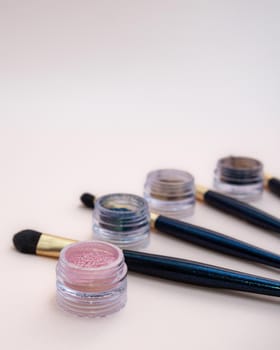 Composition with decorative makeup products golden brushes and colorful eye shadows on pastel pink background. photo