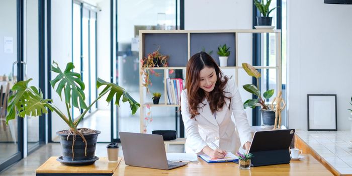 Asian business woman having video call with business team to consult about business plan of company. Online team meeting video conference