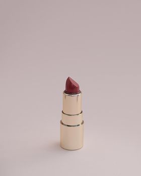 red lipstick in a gold case on a pink background. photo