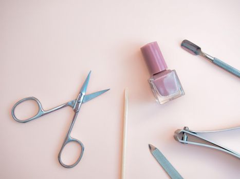 A set of cosmetic tools for manicure and pedicure on a pink background. Gel polishes, nail files, manicure scissors. photo