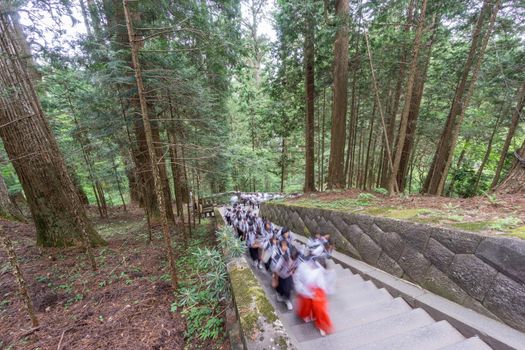 Wide view of blurred pupils visiting Japanese temple, climbing stairs