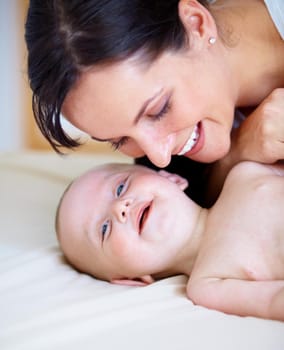 Happy baby boy smiling as his mother leans down to close to him.