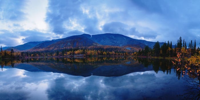 Reflection of mountains and clouds in the calm surface of the lake. Peaceful landscape. Khibiny. photo