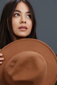 beautiful woman brown hat hand gestures fashion emotions Gray background. High quality photo