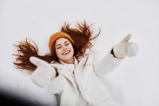 Happy young woman winter clothes with a hat lies on the snow winter holidays. High quality photo