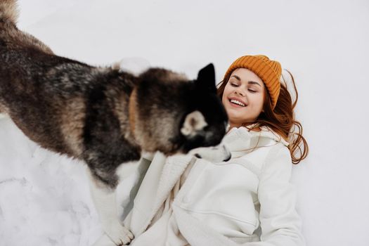 cheerful woman in the snow playing with a dog fun friendship winter holidays. High quality photo