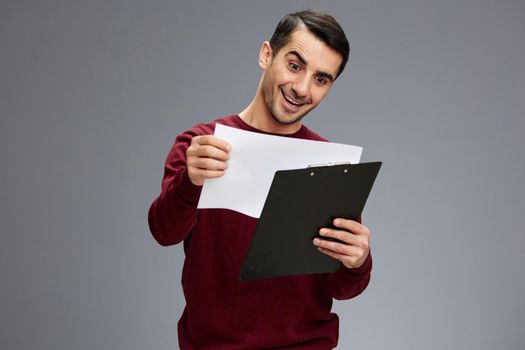 handsome man looking at a piece of paper with a smile posing red sweater work elegant style. High quality photo