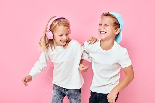 girl with headphones next to boy dancing entertainment pink color background. High quality photo