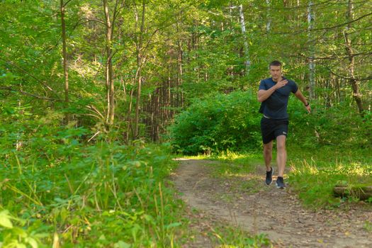 A man athlete runs in the park outdoors, around the forest, oak trees green grass young enduring athletic athlete healthy trail endurance recreation marathon, woods man. Autumn leisure spring, feet stretches