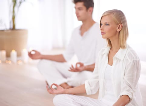 Two people sitting in the lotus position in a yoga studio.