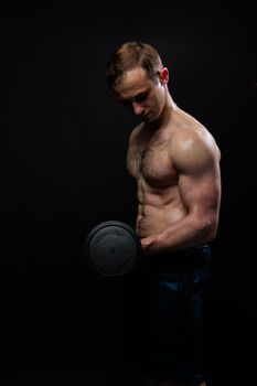 Man on black background keeps dumbbells pumped up in fitness sexy arm weight exercise heavy, shirtless Lift people fit