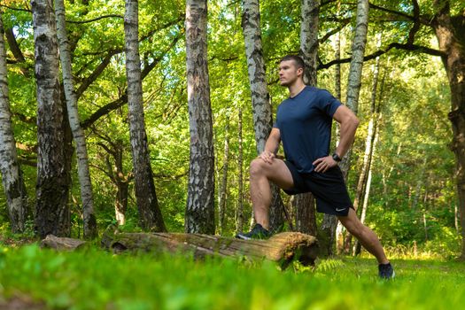 A young enduring athletic athlete is doing stretching in the forest outdoors, around the forest, oak trees.active jogger fit person jog, park outside. Autumn energy running, distance stretches