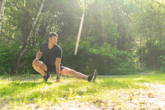 A young enduring athletic athlete is doing stretching in the forest outdoors, around the forest, oak trees.active athlete forest, fitness outdoor athletic wellness motion, jogging wellbeing. body runners stretches