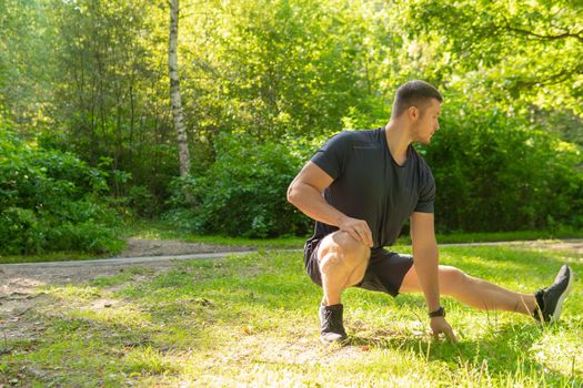 A young enduring athletic athlete is doing stretching in the forest outdoors, around the forest, oak trees.active sport forest, fitness legs woods outside. Autumn leisure running, morning stretches