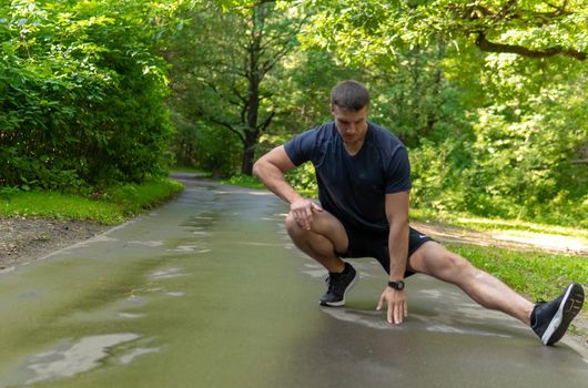 A young enduring athletic athlete is doing stretching in the forest outdoors, around the forest, oak trees.run forest, fitness fit recreation Autumn body spring, stretching stretches