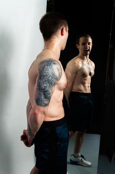Man on black background keeps dumbbells pumped up in fitness active sexy black, athlete muscular strong lifting healthy lifestyle. handsome power, human fit In mirror reflection, the body is pumped up