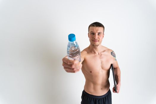 Male drink-water fitness is pumped with a towel on a white background isolated strong athlete lifestyle, water energy person, break cardio. Towel copy pace, caucasian one muscle