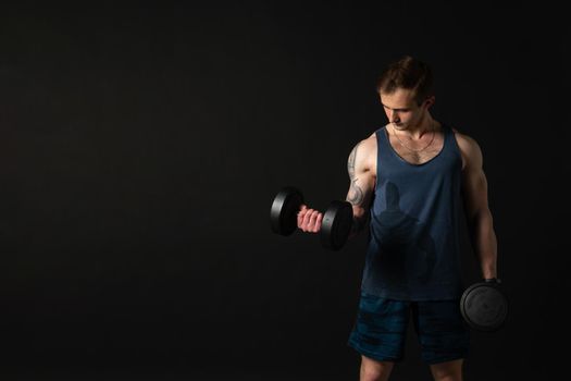 Man on black background keeps dumbbells pumped up in fitness active chest strong hold heavy, shirtless weightlifting. Young handsome people fit