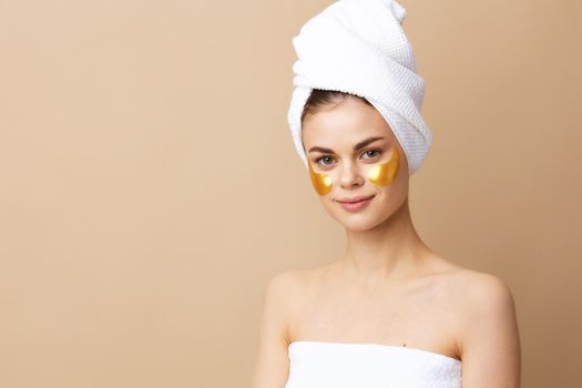 beautiful woman golden patches on the face with a towel on the head beige background. High quality photo