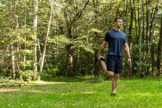 A man athlete runs in the park outdoors, around the forest, oak trees green grass young enduring athletic athlete healthy athlete lifestyle trail wellness motion, park wellbeing. Summer body spring, feet stretches