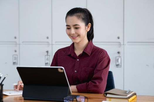 A beautiful woman smiling happily uses a sales profit calculator on the screen of a tablet after increase in sales growth