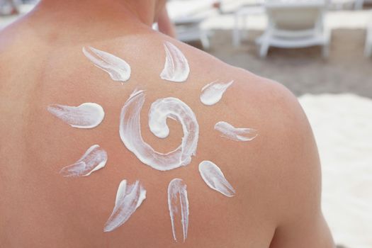 Close-up of persons back with sunscreen picture of sun on it, protect skin from damage. Prepare for sunbathe with spray. Cosmetology, beach, summer concept