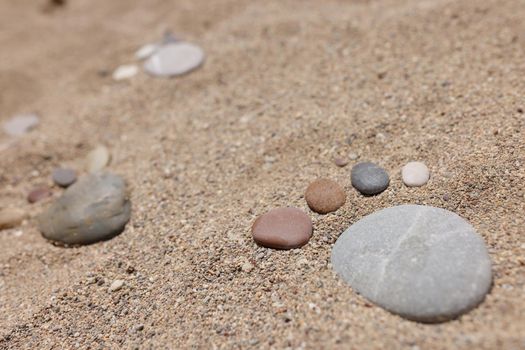 Close-up of stone put in human foot shape on sand, hot summer day, coastline, sandy beach. Summertime, beachfront, nature, wildlife, digging, shore concept