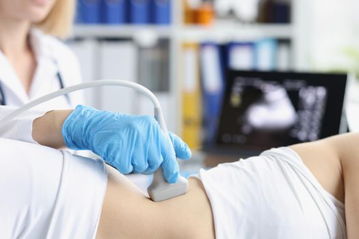 Close-up of professional medical worker examine clients body with ultrasound tool. Pregnant woman on planned checkup. Medicine, scanning, clinic concept