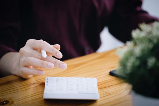 A female company employee is using a calculator to calculate sales income