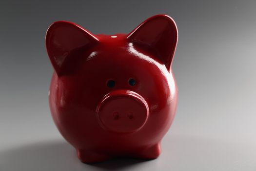 Close-up of red piggybank container on grey surface, thing to save money, ceramic animal. Finance, saveup for future, success, economy, investment concept