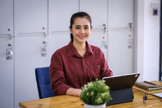 A beautiful woman smiling happily uses a sales profit calculator on the screen of a tablet after increase in sales growth