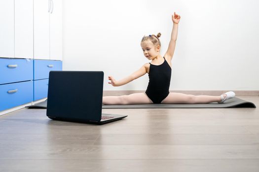 online rhythmic gymnastics. girl preschooler doing rhythmic gymnastics with a trainer online