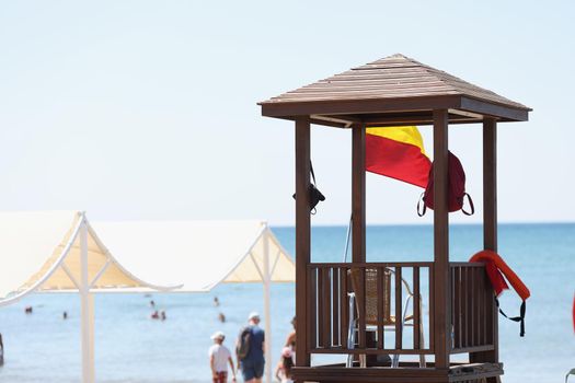 Portrait of beach with baywatch tower, no lifeguard person on post, people swimming in ocean. Baywatch, save life, observer, protection, summertime concept