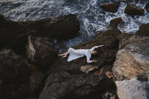 sensual woman lying on her back on a rocky seashore view from above. High quality photo