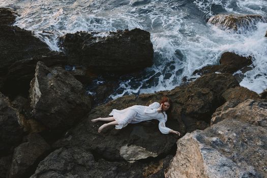 attractive woman with long hair lying on rocky coast with cracks on rocky surface nature landscape. High quality photo