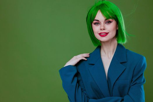 Positive young woman wearing a green wig blue jacket posing green background unaltered. High quality photo