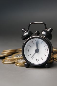 old alarm clock and coins on black background