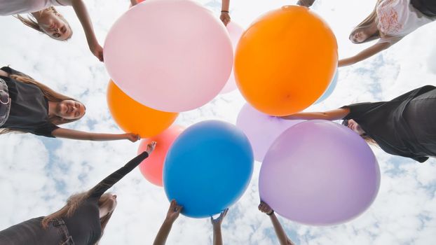 Friendly girls connect big balloons together in the park