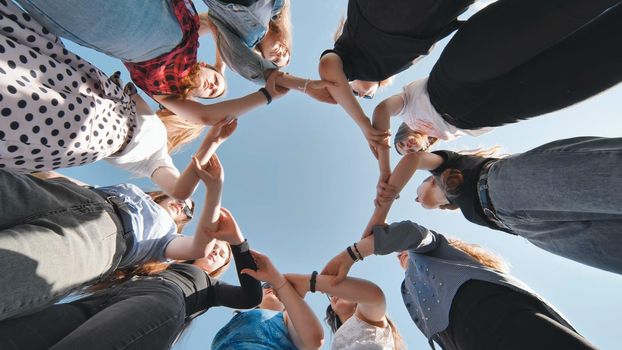 A group of girls makes a circle shape holding each other's hands