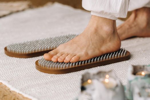 The man's feet are next to boards with nails. Yoga classes.