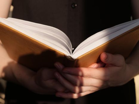 Book in hands close up in daylight. The person is reading an interesting book