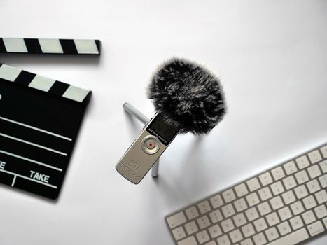 Record audio inside on zoom h1 recorder with dead cat in recording studio on white background in natural daylight. The background shows objects such as Clapperboard and keyboard. You can use this photo in any project related to sound recording, podcast, recording studio, interview or journalistic activity.. High quality photo