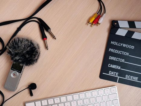 Flat with a copy space on a wooden background for video production or sound studio. Record audio inside on a zoom h1 recorder with a dead cat in the studio in natural daylight. The background shows items such as Clapperboard, keyboard, cord, cable, 3.5, mini jack.