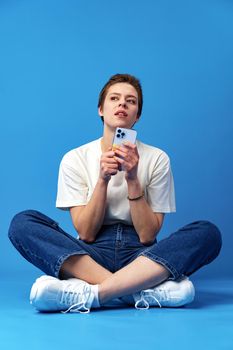 Happy nice girl using cellphone isolated over blue background, close up