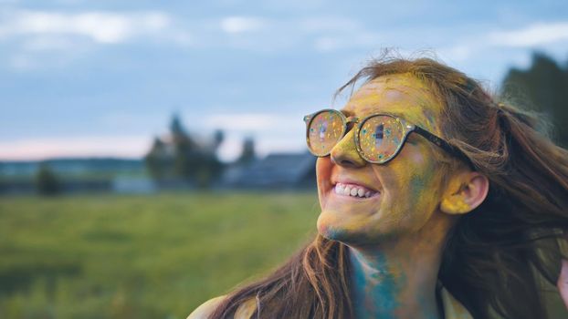 Cheerful girl posing smeared in multi-colored powder