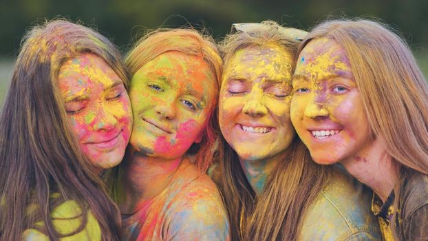 Cheerful girls posing smeared in multi-colored powder. Close-up faces