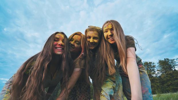 Cheerful girls are posing smeared in multi-colored powder